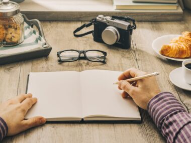 Writer at a desk writing in a journal