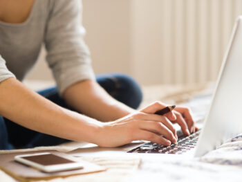 Young woman sitting and working on a laptop in her home office.